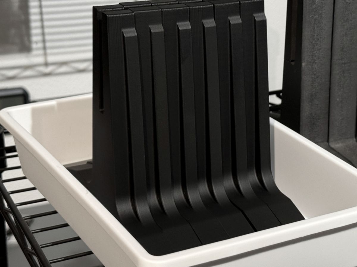 A tub of printed slotted legs beside the foam originals they replace